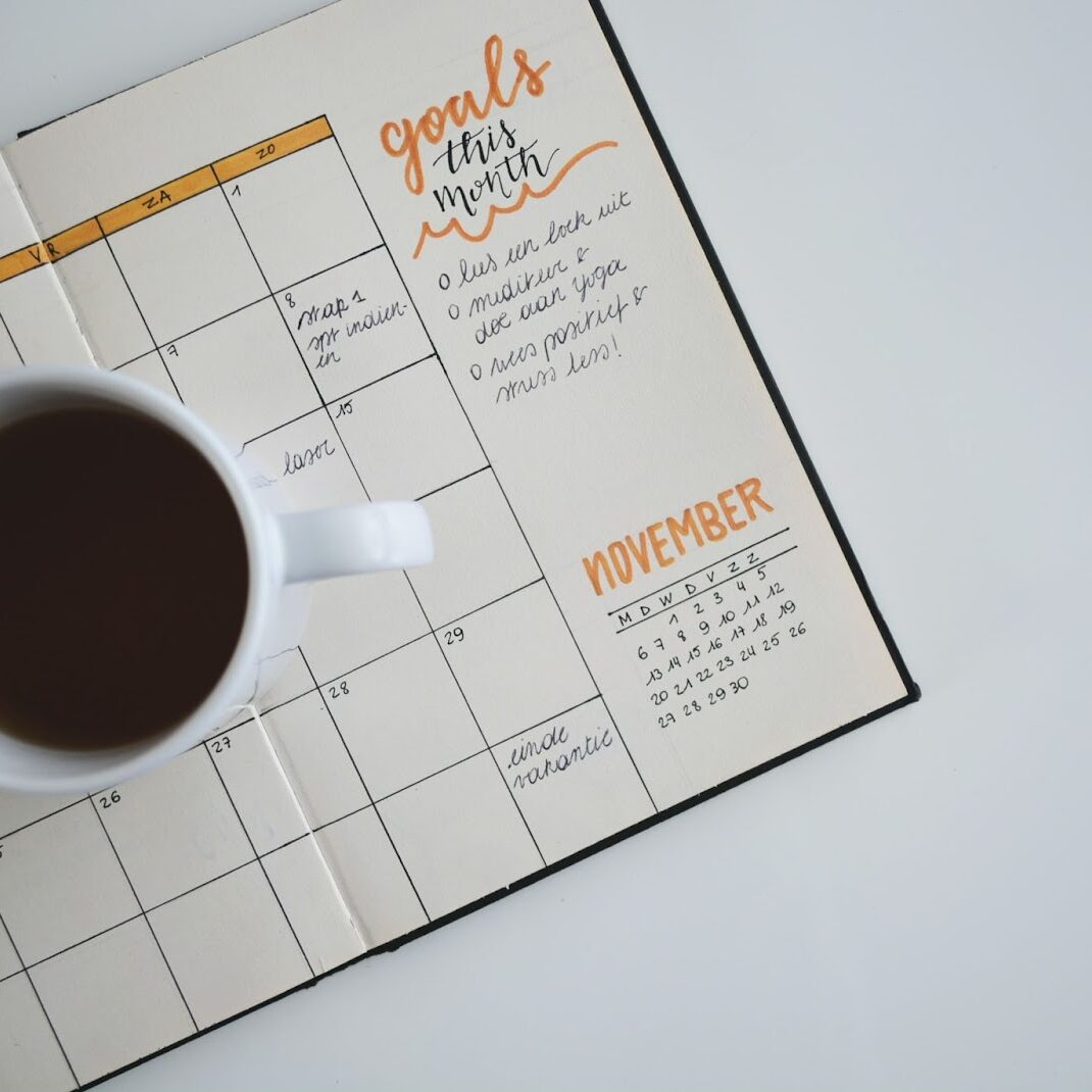 An image of a coffee mug sitting atop a monthly planner.