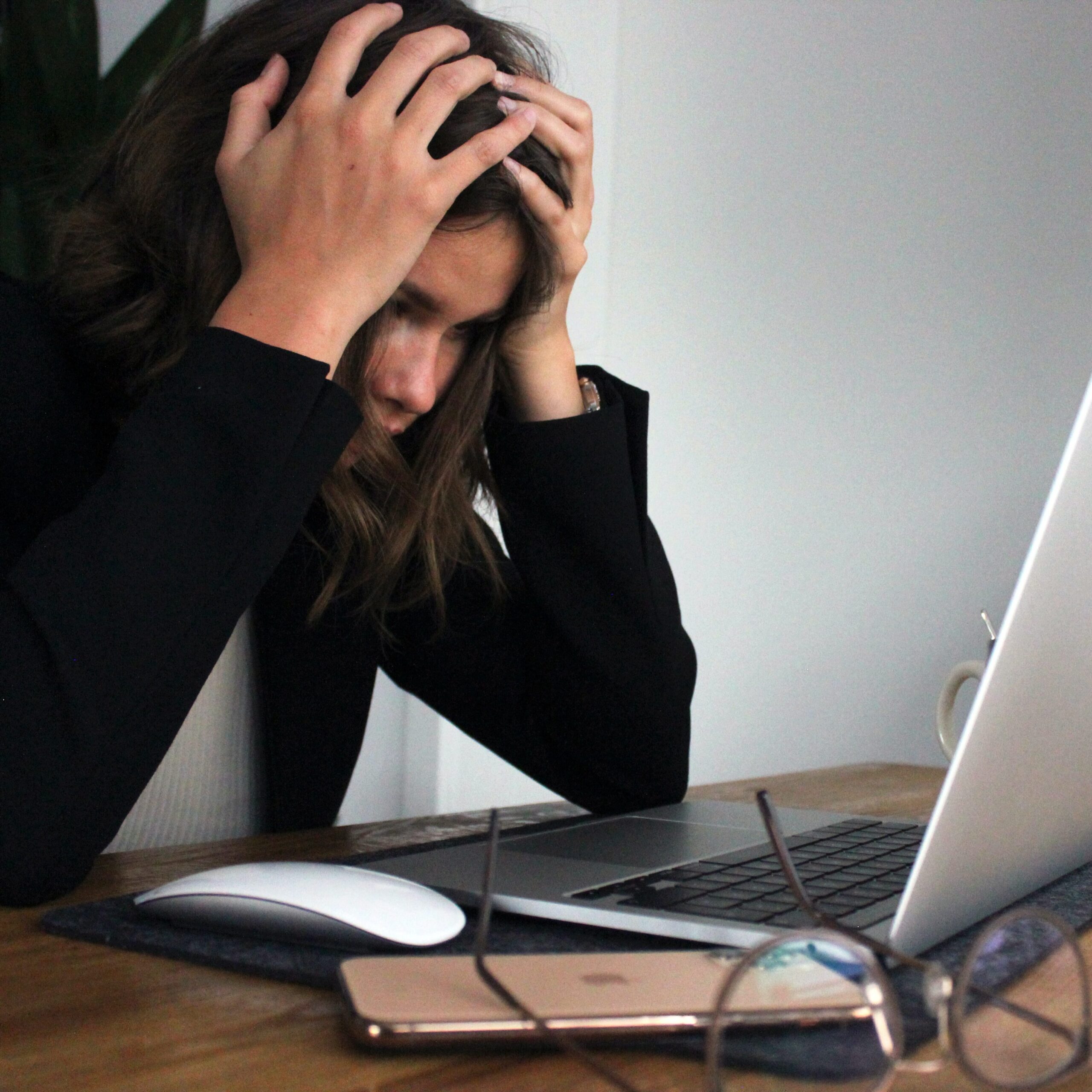 Woman with head in her hands looks stressed while staring at computer screen 