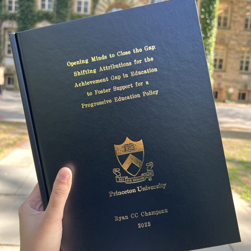 Photo of Ryan CC Champeau's undergraduate thesis - bound, hardcopy print book with gold lettering of thesis title: Opening Minds to Close the Gap: Shifting Attributions for the Achievement Gap in Education to Foster Support for a Progressive Education Policy