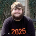 Photo of young man smiling at camera wearing a Princeton '25 shirt. 