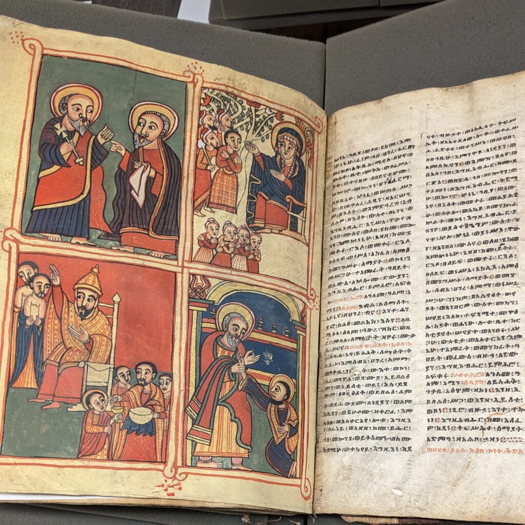 Image shows an Ethiopic book, opened to pages featuring pictures of saints and text in Ge'ez (Classical Ethiopic)