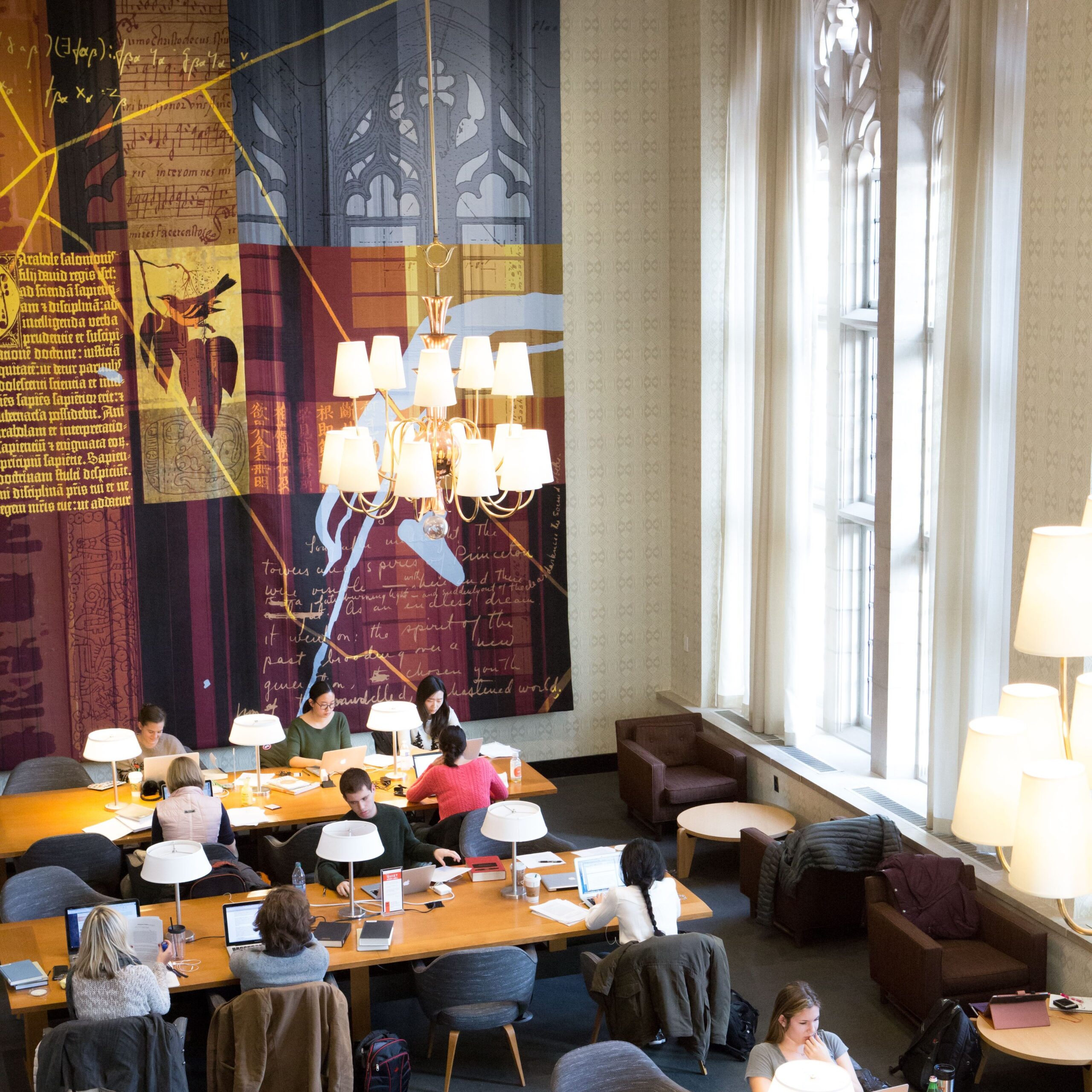 Image taken from above of Firestone Library, with ten individuals studying or working on laptops.