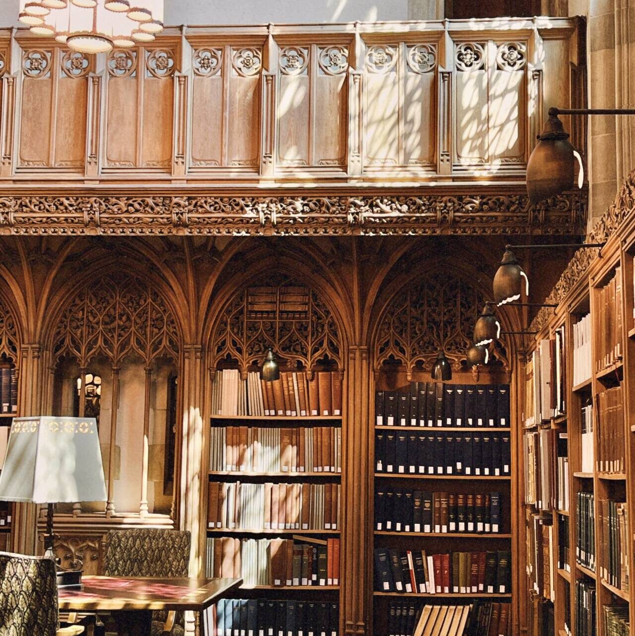 Empty corner of the Firestone Library with books lining the shelves and a table and lamp in the foreground.