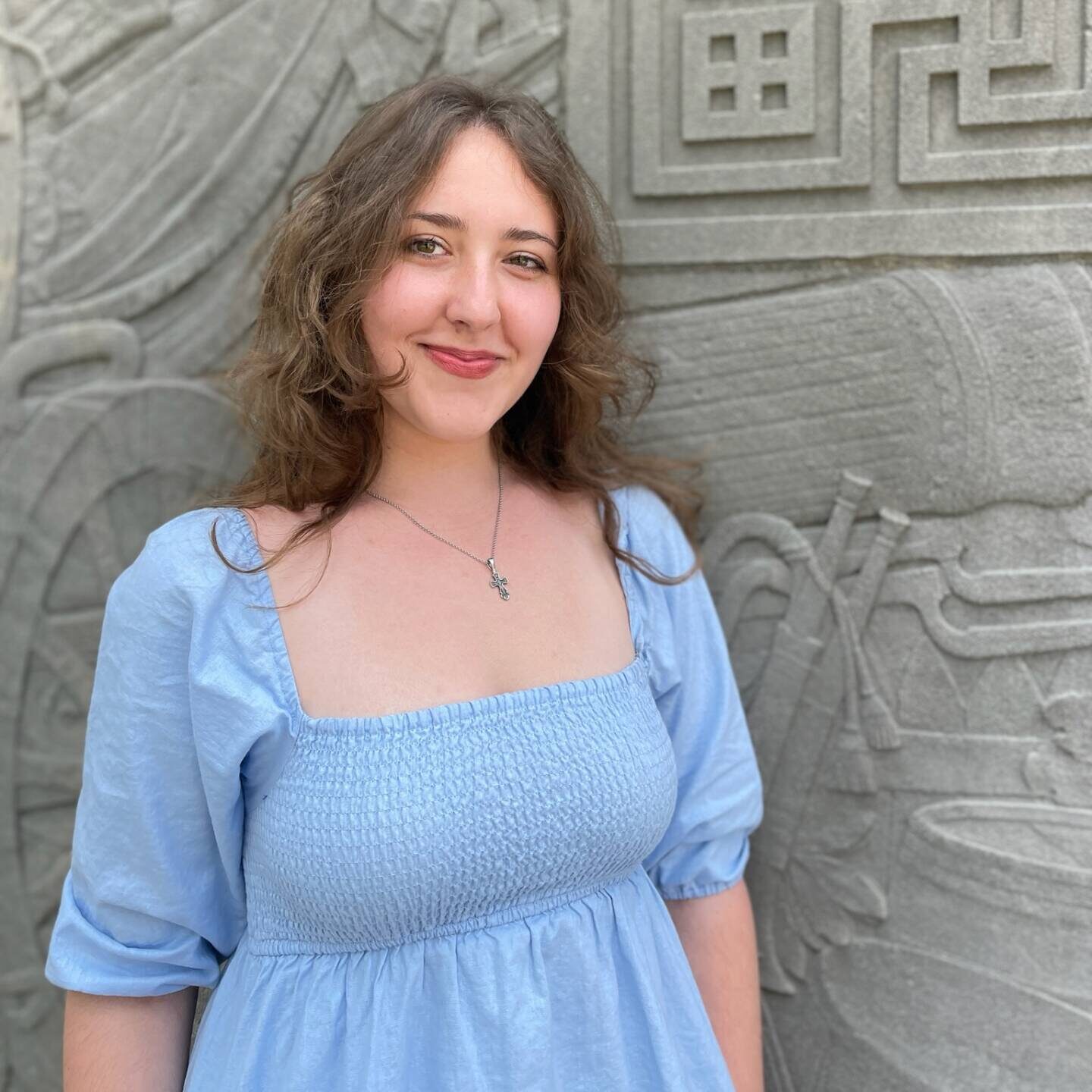 Photo provided by Katya Grygorenko Image of interview subject, Katya Grygorenko in front a stone wall with artictic carvings.
