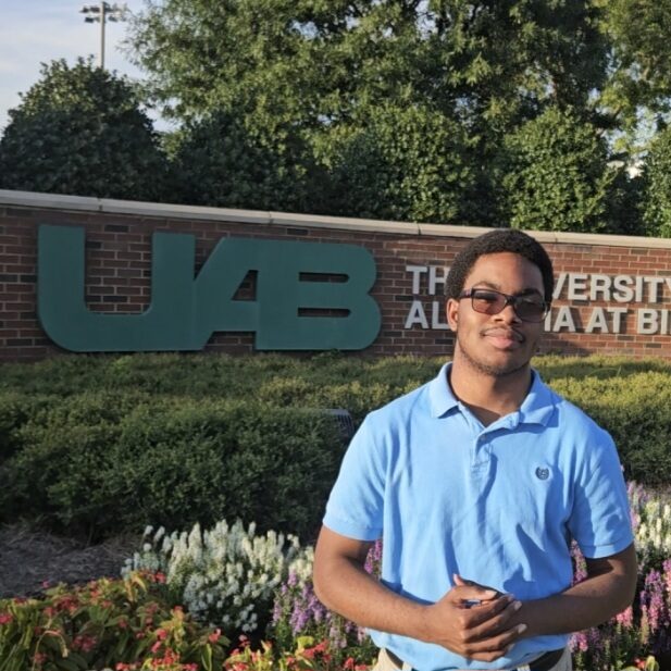 Photo Taken by Stanley Stoutamire Stanley Stoutamire standing in front of a university sign.