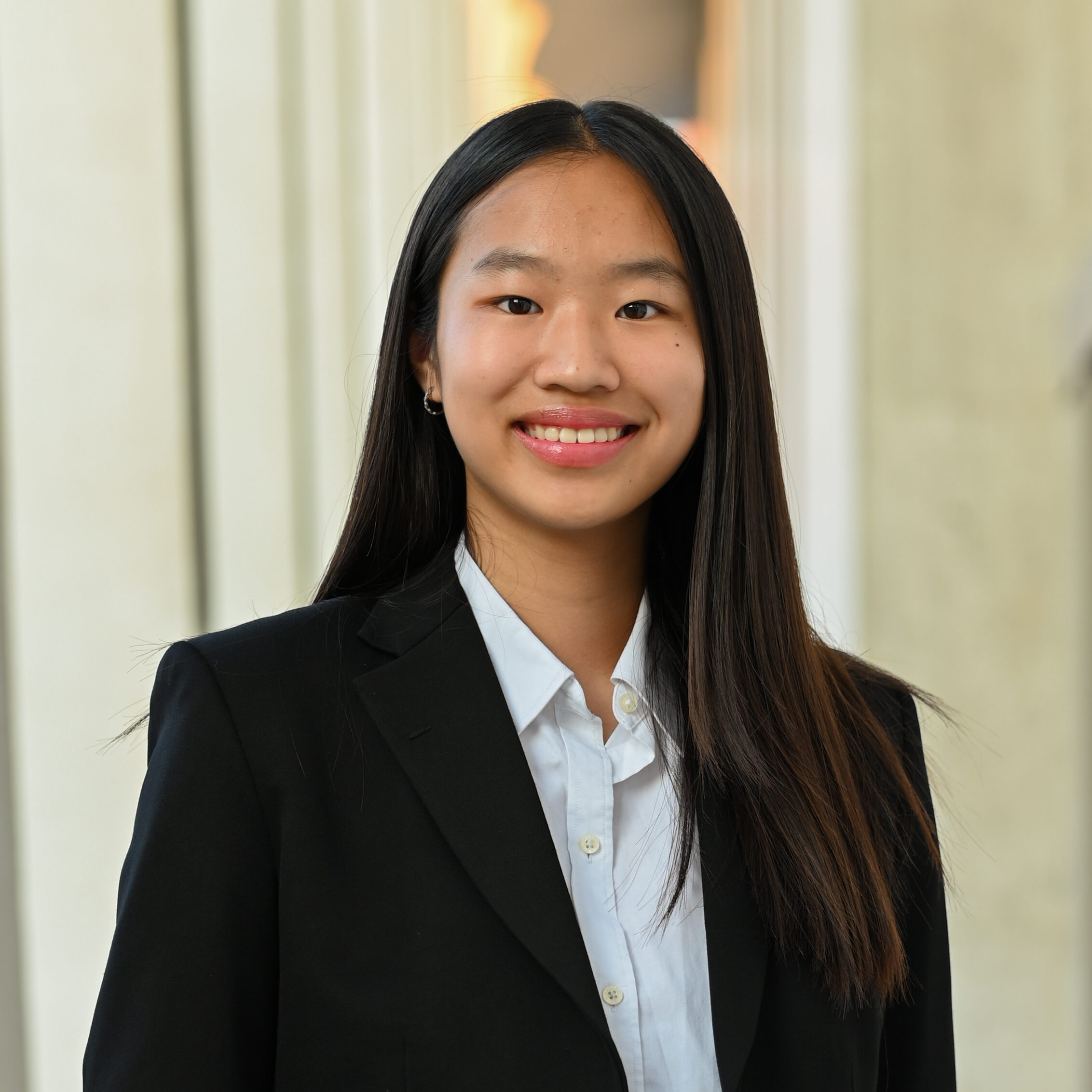 Photograph of young woman in suite with long hair smiling at camera